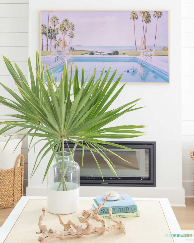Coastal coffee table styling with a rattan Serena & Lily coffee table, driftwood, coastal coffee table books, and a colorblock vase filled with saw palms.