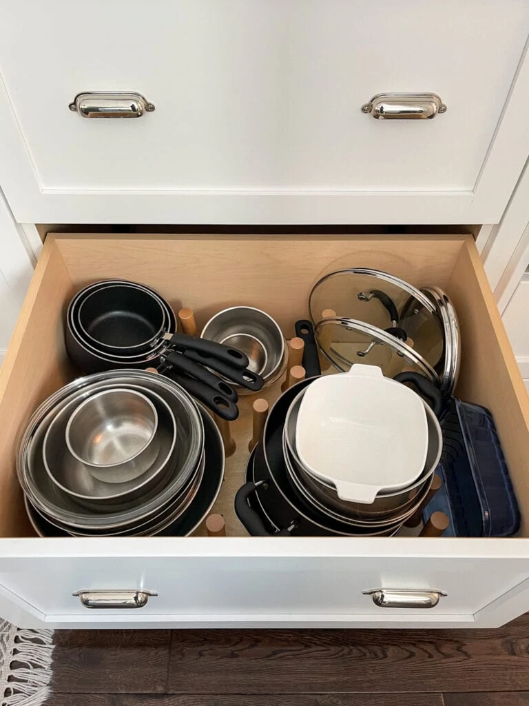 A kitchen drawer that stores pots, pans and mixing bowls.