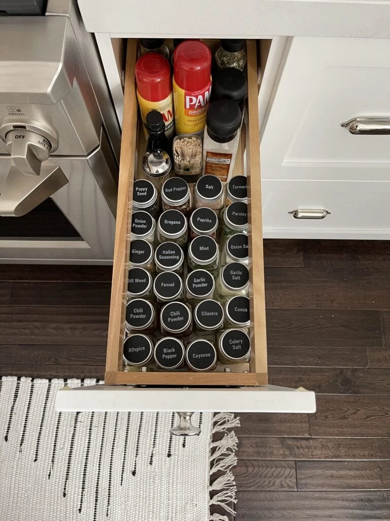 An organized spice drawer with spice jars labeled on the lid for easy viewing.
